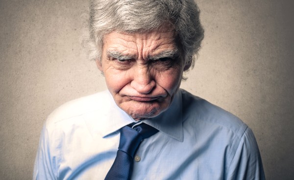 A grumpy faced man, resisting going into hypnosis.
