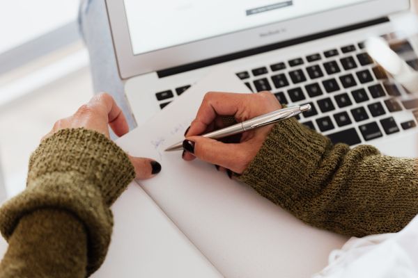 Hypnotherapist writing her hypnotherapy script on a notepad, before transcribing it on a computer