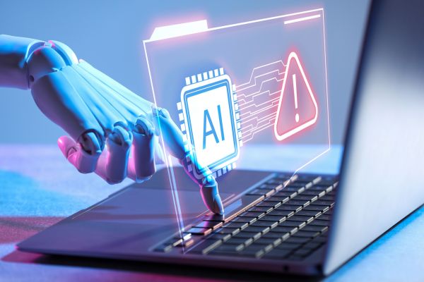 A robot hand pushing a button on a laptop, with an AI Warning symbol