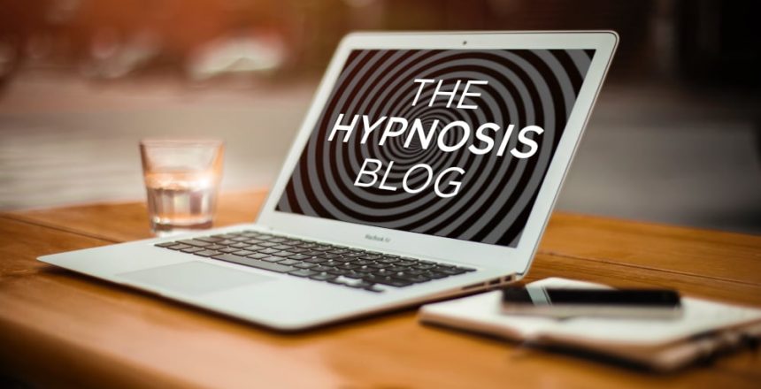 The hypnosis blog Laptop computer on a clean wooden desk showing the words 'the hypnosis blog' on a spiral background